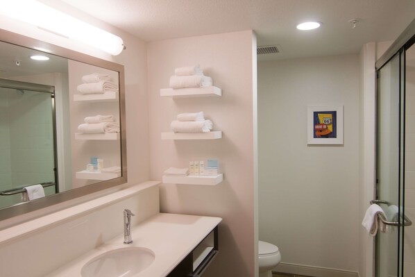 A bathroom with a sink, mirror, and shelves with towels.