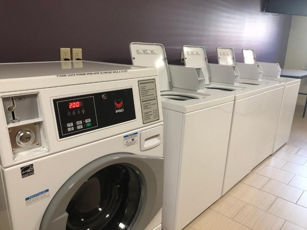 A row of white washing machines with a digital display, a control panel, and a label that reads 'NOTICE'.
