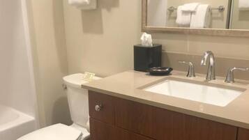 Une salle de bain équipée de toilettes, d’un lavabo, d’un miroir et d’un porte-serviettes.
