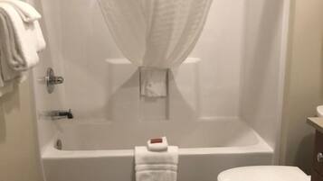 A bathroom with a bathtub, toilet, and shower curtain.
