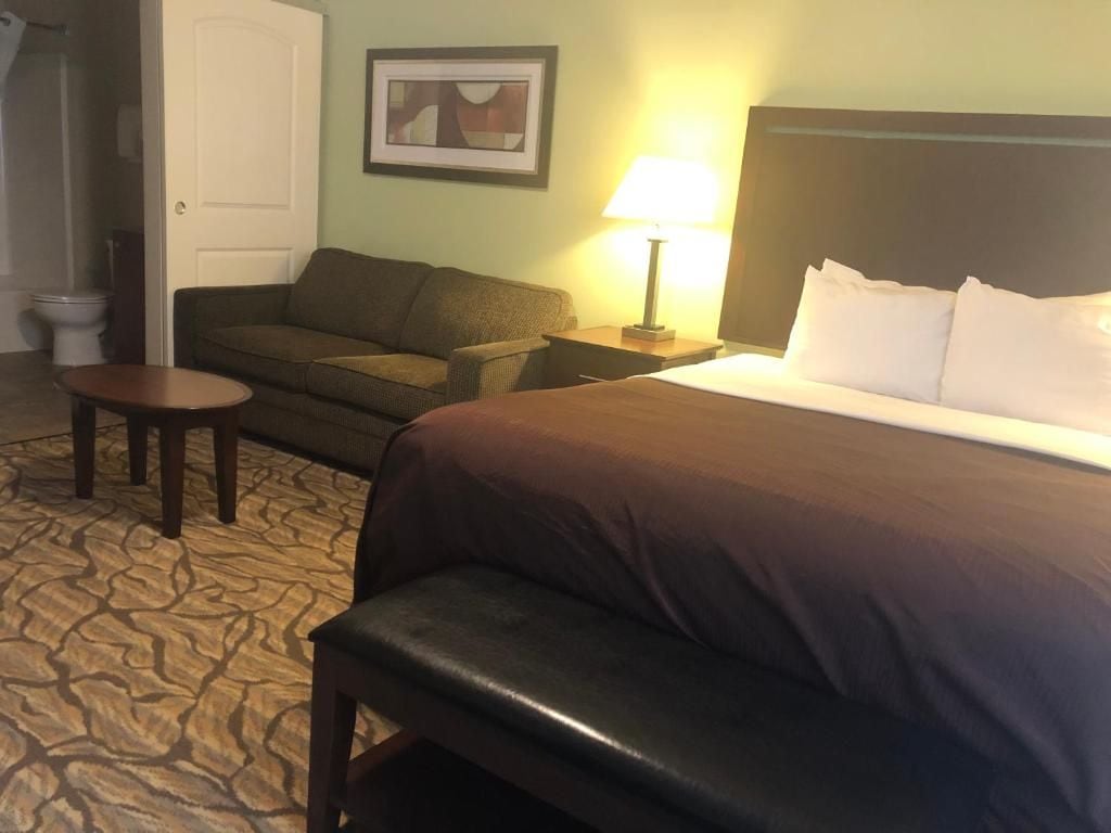 Ein Hotelzimmer mit Bett, einer Couch, einem kleinen Tisch und einer Lampe.