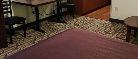 A hotel room with a bed, a desk, a chair, a lamp, a microwave, and a sink.
