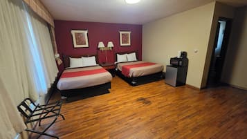 Hotelkamer met twee bedden, een bureau, een stoel, een magnetron en een deur naar een andere kamer.