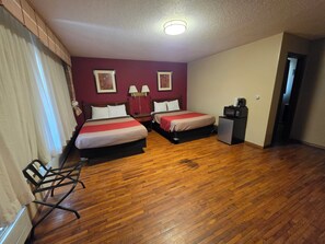 A hotel room with two beds, a desk, a chair, a microwave, and a door leading to another room. - Eastwood Inn Of Wadena (Wadena)
