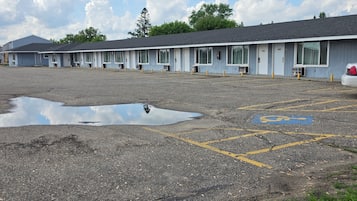 A motel with a row of rooms, a parking lot with a visible handicap parking space, and a large puddle on the ground.