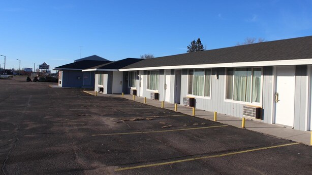 A row of motel rooms with a parking lot in front. - Eastwood Inn Of Wadena (Wadena)