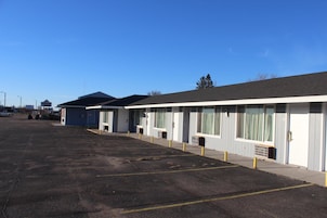Una hilera de habitaciones de motel frente a un estacionamiento.