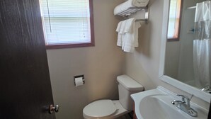 A bathroom with a toilet, sink, and window.