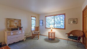 A room with a dresser, a rocking chair, a small table with a lamp, and a wicker chair. - Augusta 4 (Bend)