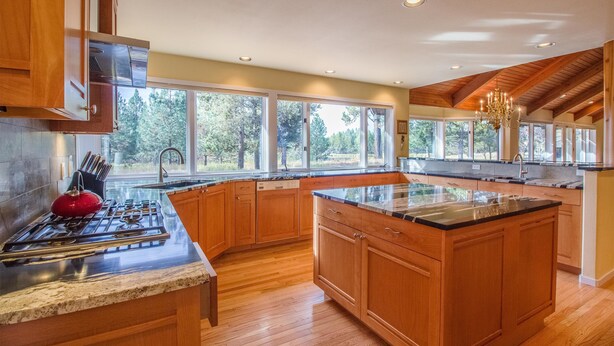 A spacious kitchen with wooden cabinets, a granite countertop, and a large island. - Bachelor 5 (Bend)