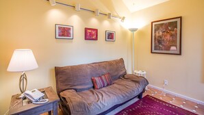 A cozy room with a brown sofa, a small table with a lamp and phone, and a patterned rug. - Bachelor 5 (Bend)