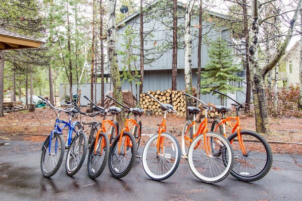 Bicycles are parked outside this building, which features a wooden deck and a stack of firewood.