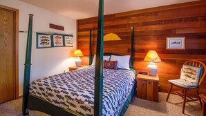 Una habitación con cama con dosel, paredes de madera, cuadros de peces enmarcados y una silla con estampado de peces.