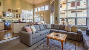 A spacious living area with a large sectional sofa, a wooden coffee table, and a kitchen area with a dishwasher and cabinets. - Big Leaf 25 (Bend)