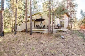 Eine Holzhütte mit einer Terrasse, umgeben von hoch aufragenden Kiefern.