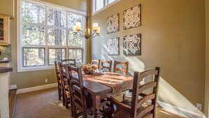 A dining area with a wooden table and chairs, a chandelier, and artwork on the wall. - Big Leaf 25 (Bend)