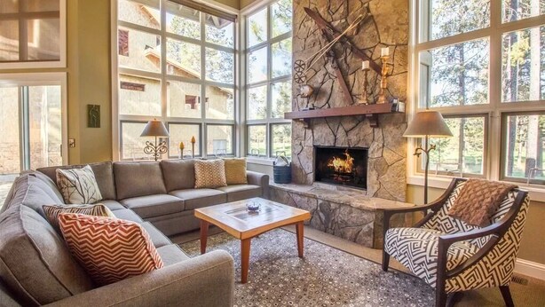 A cozy living room with a stone fireplace, large windows, and comfortable seating. - Big Leaf 25 (Bend)
