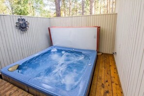 Ein Whirlpool mit einer Holzterrasse und einer weißen Wand mit vertikalen Linien.