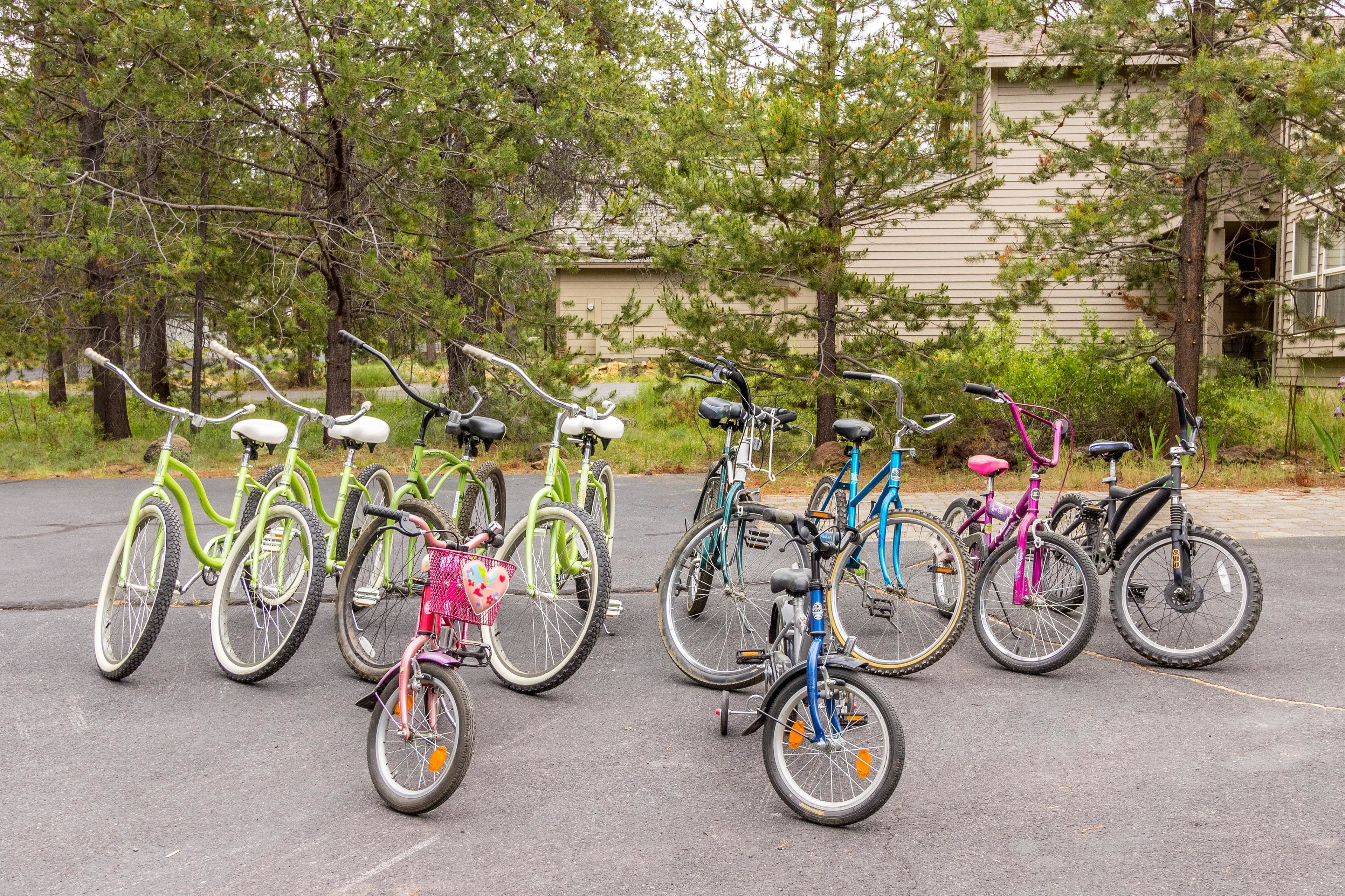 A row of bicycles parked in a parking lot with trees and a building in the background.