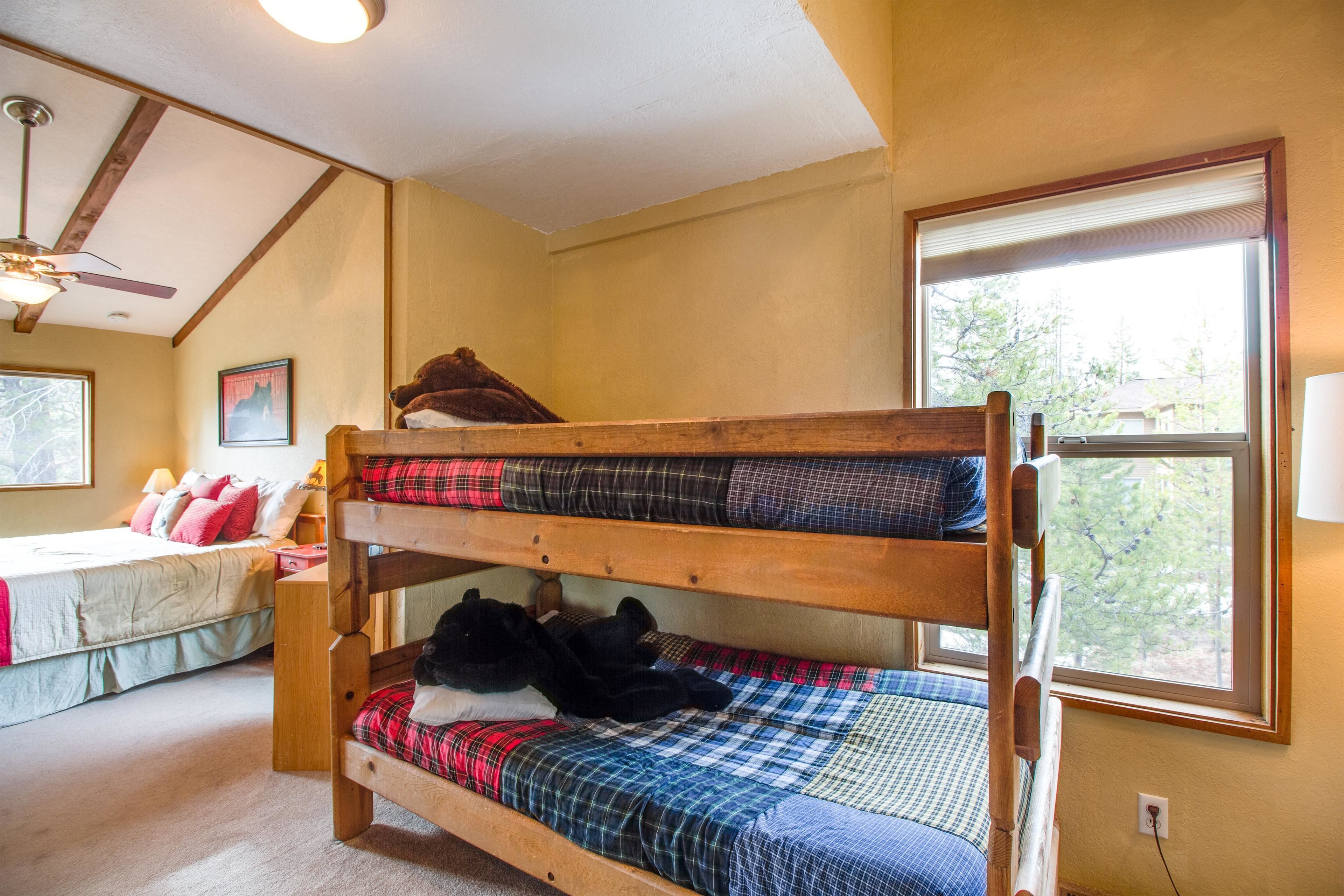 Un lit superposé avec vue sur la fenêtre, un lit séparé avec des oreillers et un ventilateur de plafond.