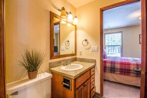 Un baño con lavabo, espejo y tocador de madera.