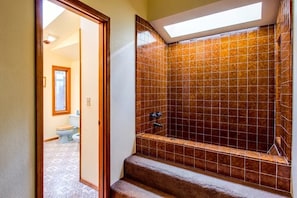 A bathroom with a tiled shower, a visible toilet, and a skylight. - Catalpa 2 (Bend)
