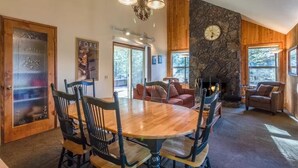 A cozy interior with a wooden dining table, chairs, a fireplace, and a stone accent wall. - Lark 7 (Bend)