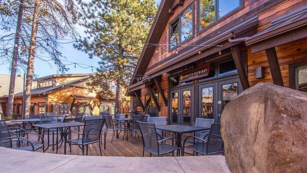 A wooden building with outdoor seating and a large rock in the foreground. - Diamond Peak 23 (Bend)