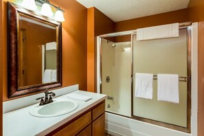 A bathroom with a sink, mirror, and shower.