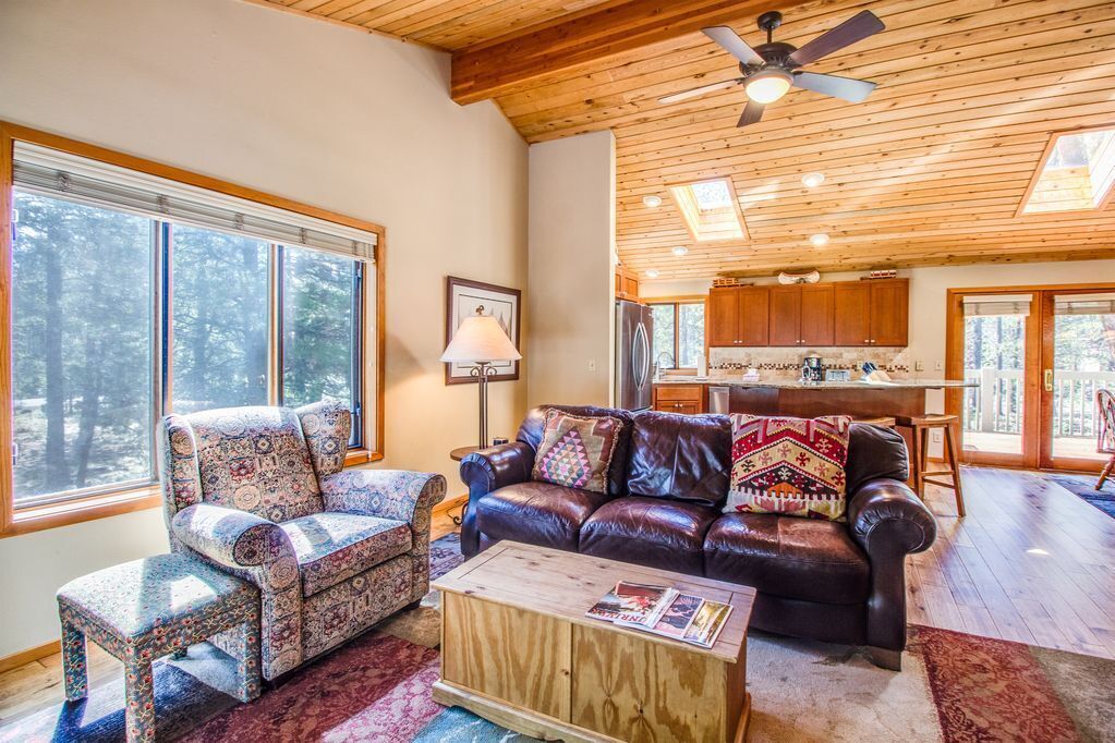 A cozy living room with a patterned armchair, a leather sofa, and a wooden coffee table.