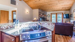A kitchen with a built-in stove, a stone fireplace, and a large window. - Diamond Peak 4 (Bend)