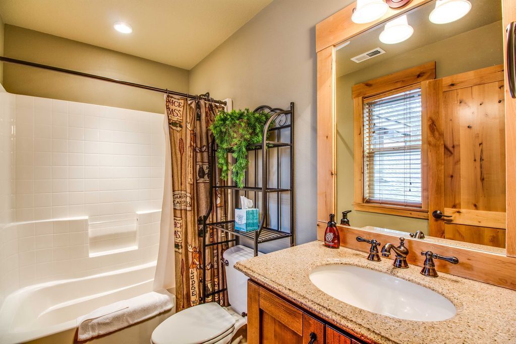 A bathroom with a bathtub, a wooden vanity with a sink, and a mirror.