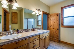 A bathroom with two sinks, wooden cabinets, and a large mirror. - Duck Pond 3 (Bend)