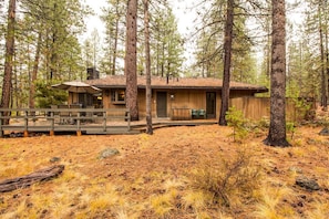 A cabin with a deck, surrounded by tall pine trees. - East Butte 10 (Bend)