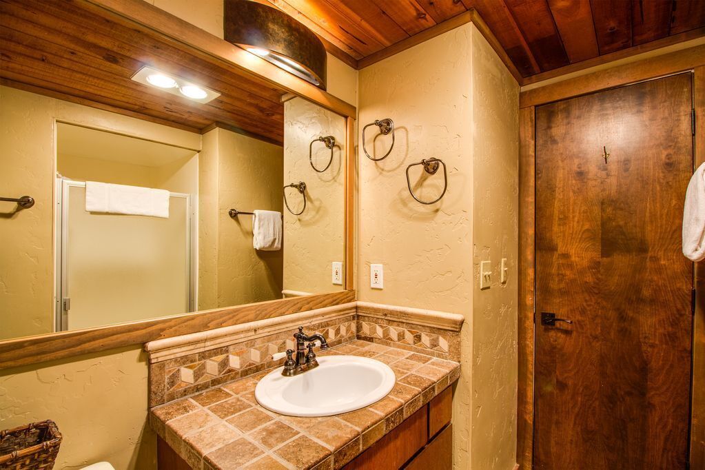 A bathroom with a wooden ceiling, a white sink, and a large mirror.