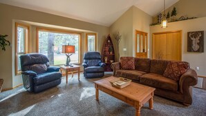 A spacious living room with a leather recliner, a brown sofa, and a wooden coffee table. - Red Cedar 49 (Bend)