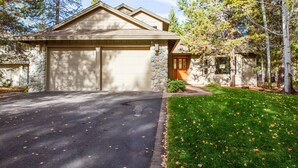 A two-story house with a stone facade, a garage, and a well-maintained lawn. - Red Cedar 49 (Bend)