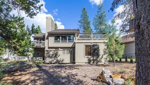 A two-story house with a balcony, surrounded by trees and a gravel driveway. - Rogue 19 (Bend)