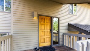 A wooden door with a small porch and a black mat at the entrance. - Rogue 19 (Bend)