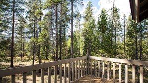 A wooden deck with a railing overlooking a forested area. - Rogue 19 (Bend)