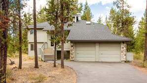 A two-story house with a stone foundation garage, a covered porch, and a driveway leading to the garage. - Splitrock 11 (Bend)