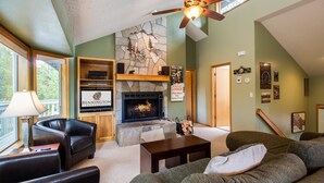 A cozy living room with a fireplace, leather furniture, and a stone accent wall. - Splitrock 11 (Bend)