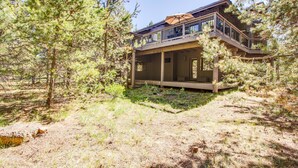 A two-story wooden cabin with a balcony, surrounded by pine trees. - Sumac 9 (Bend)