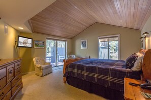 A bedroom with a large bed, a wooden dresser, a chair, and a desk with a lamp. - Tan Oak 29 (Bend)