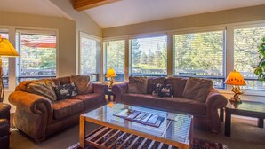 A living room with two leather sofas, a glass coffee table, and two lamps. - Tan Oak 15 (Bend)