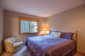 Quarto com uma cama, uma cadeira, uma janela e uma mesa de cabeceira com abajur.