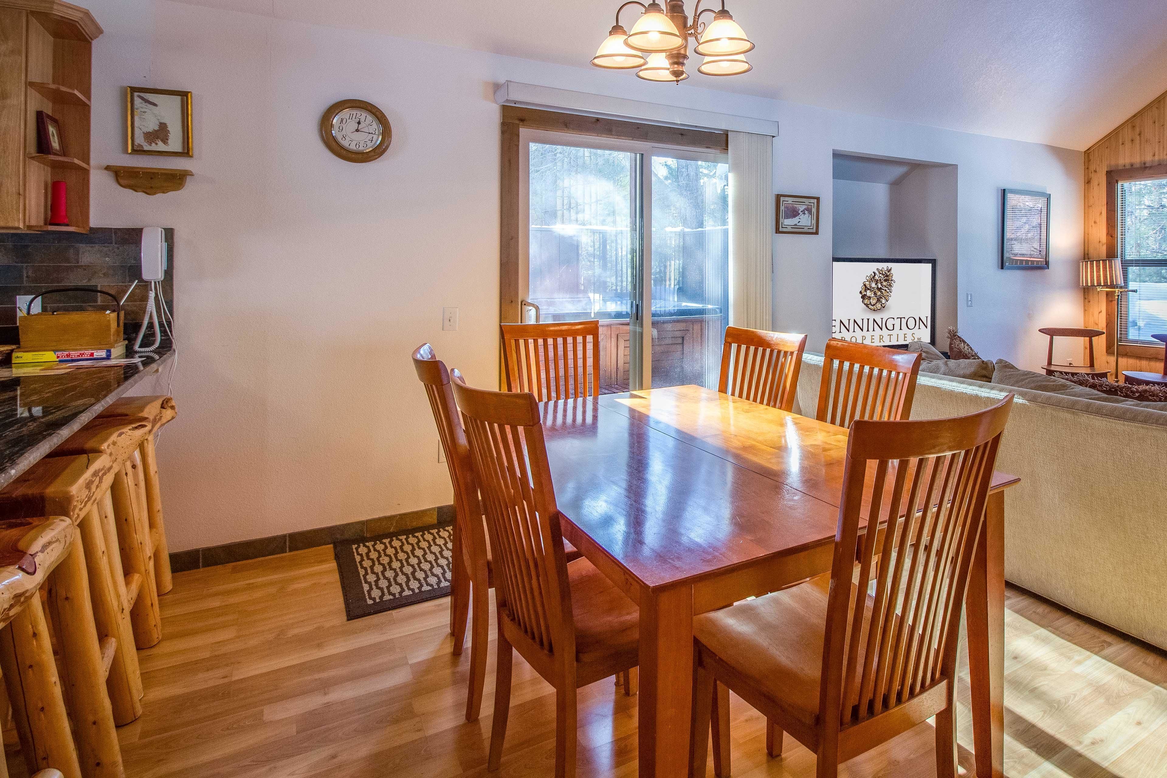 A dining area with a wooden table and chairs, a kitchen area with a wooden counter and cabinets, and a large window with a view of the outdoors.