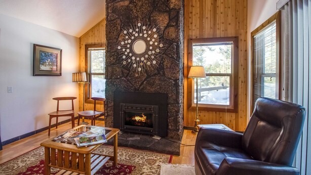 Una sala de estar acogedora con chimenea de piedra, paredes de madera y un sofá de cuero.