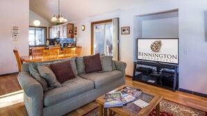 Un salón con sofá gris, mesa de centro de madera y un televisor que muestra 'BENNINGTON PROPERTIES LLC'.