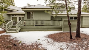 A two-story house with a front porch, a staircase, and a snow-covered yard.